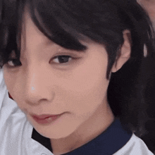 a close up of a girl 's face with a white shirt on .