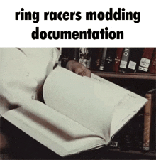 a person is reading a book that says ring racers modding documentation on it .