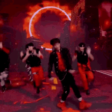 a group of young men are dancing on a stage in front of a fire .
