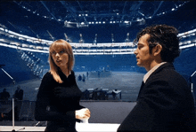 a man and a woman standing in front of a large stadium