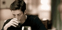 a man is drinking a glass of whiskey at a table .
