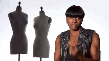 a man in a leather vest is standing in front of three mannequins