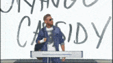 a man is standing in front of a wall that says cassidy