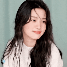 a woman with long black hair is smiling and wearing a white sweater