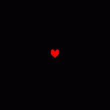 a red heart with wings is glowing in the dark on a black background .