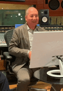 a man in a suit sits at a desk with a laptop