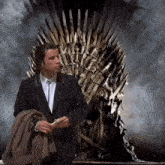 a man in a suit sits in front of a throne