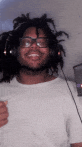 a man with dreadlocks wearing headphones and a white shirt is smiling