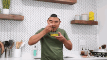 a man is eating something in a kitchen with the words made in animatica on the bottom right