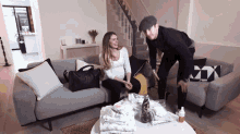 a pregnant woman sits on a couch while a man stands in front of her