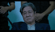 a man in a suit is sitting in front of a group of people