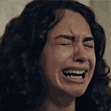 a woman with curly hair is crying with her eyes closed