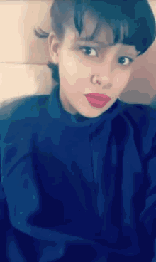 a woman with red lips and a nose ring looks at the camera