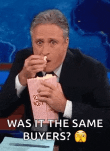 a man in a suit is eating popcorn and saying was it the same buyers ?