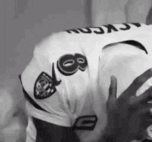 a black and white photo of a man wearing a raiders jersey and holding a football .