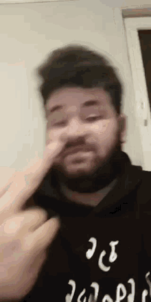 a man with a beard is blowing his nose while wearing a black shirt .