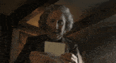 a woman standing in a dark room looking at a letter