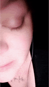 a close up of a woman 's face with her eyes closed and a tattoo on her neck that says night