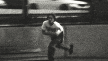 a black and white photo of a person running with a car behind them