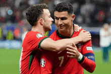 two soccer players are hugging and one has the number 7 on his shirt