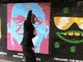 a woman stands in front of a wall with a painting of a face and a dollar sign