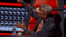 a man wearing a hat with the letter g on it is sitting in a chair