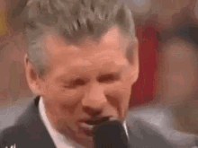 a man in a suit and tie is holding a microphone in his mouth .