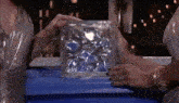 a woman is holding a clear glass block with ice in it .