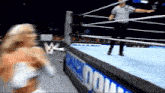 a woman in a wrestling ring with a referee and a sign that says ' wwe ' on it