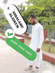 a man standing in front of a green sign that says assalamu alaikum