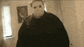 a man in a white mask is standing in a room .