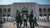 a group of people are standing in front of a building with arches