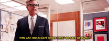 a man in a suit and tie is standing in an office and talking to another man .