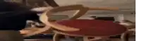a person is standing next to a wooden chair with a red cushion in a living room .