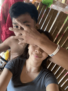 a man covering a woman 's eyes while wearing a bracelet that says ' bts ' on it