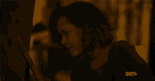 a close up of a woman 's face in a dark room with a bet logo on the bottom .