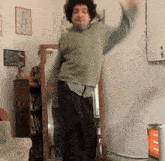 a man in a green sweater is dancing in front of a mirror in a living room