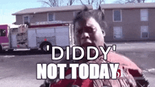a man is standing in front of a fire truck with the words `` diddy not today '' written on his face .