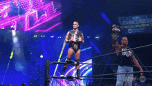 a wrestler is standing in the middle of a wrestling ring holding a championship .