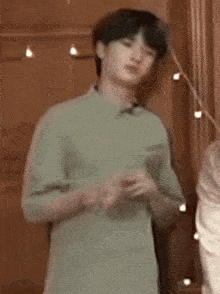 a young man in a green shirt is standing in front of a door .