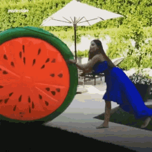 a woman in a blue dress is pushing a watermelon float