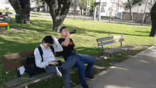 a man drinking from a bottle while sitting on a park bench