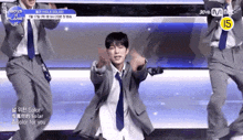 a man in a suit and tie is dancing on a stage with other men .