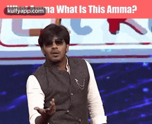 a man wearing sunglasses is standing in front of a sign that says what is this amma .