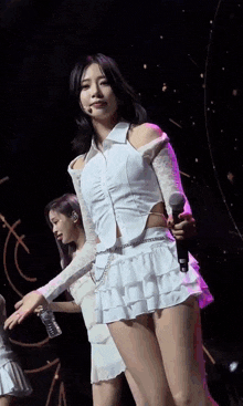 a woman in a white dress is holding a bottle of water on stage