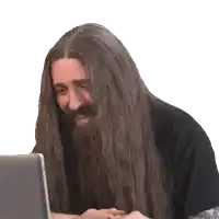 a man with long hair and a beard is looking at a laptop