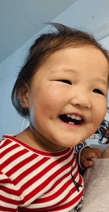 a little girl in a red and white striped shirt smiles