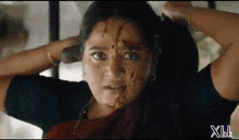 a woman with blood on her face is holding her hair in a close up .