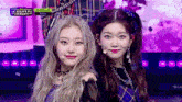 two girls are standing next to each other on a stage and smiling for the camera .