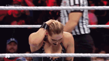 a woman is kneeling in a wrestling ring while a referee looks on